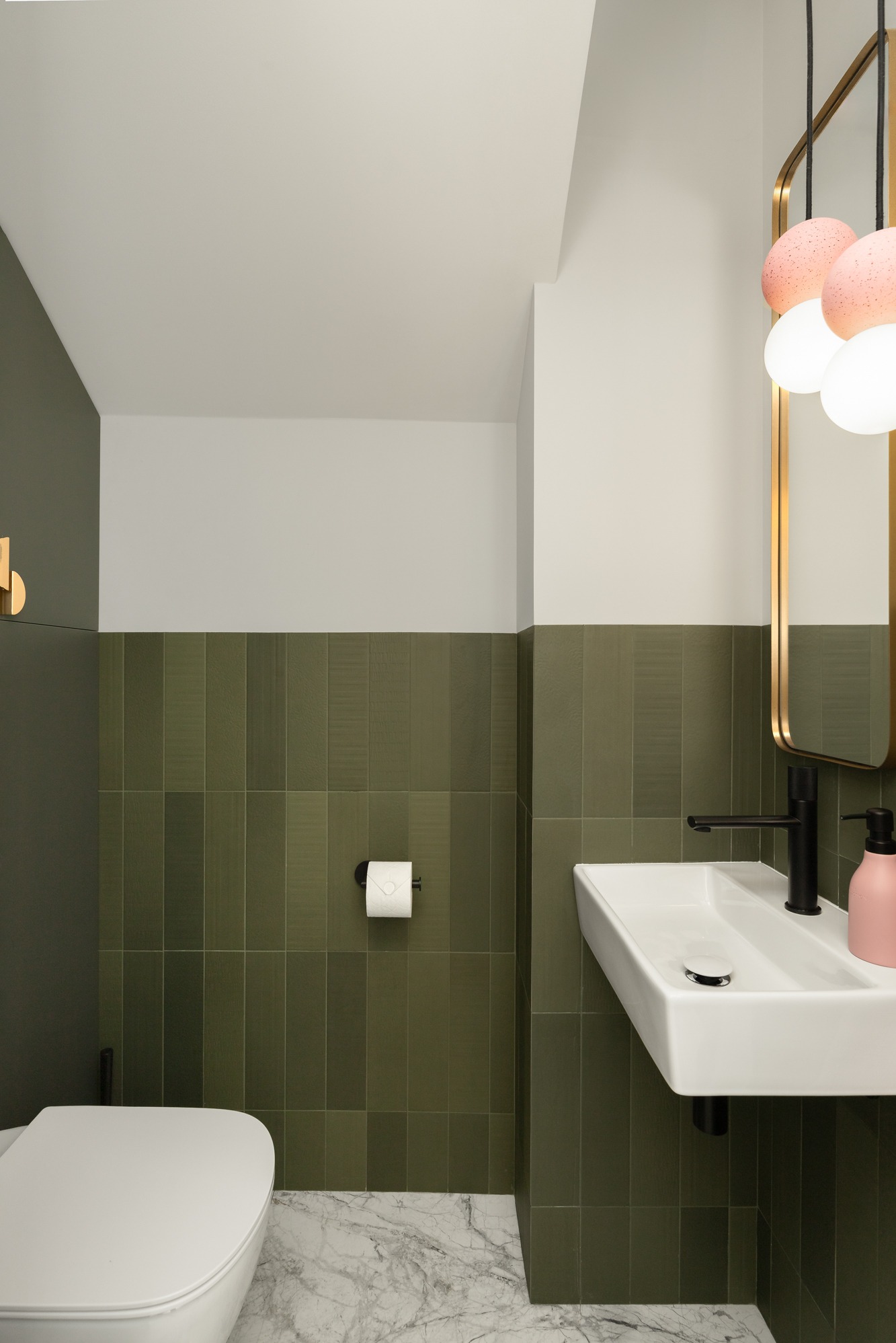 Nowoczesna łazienka w Warszawie z zielonymi, pionowo ułożonymi płytkami, białą umywalką nablatową z czarną armaturą, marmurową podłogą i okrągłym lustrem z dekoracyjnym oświetleniem.