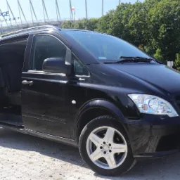 Czarny Mercedes Vito z otwartymi drzwiami przesuwnymi na tle Stadionu Narodowego w słoneczny dzień.