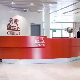 Jasne, przestronne wnętrze biura z recepcją Generali, gdzie dwie kobiety rozmawiają, a w tle widać osoby czekające na windy.