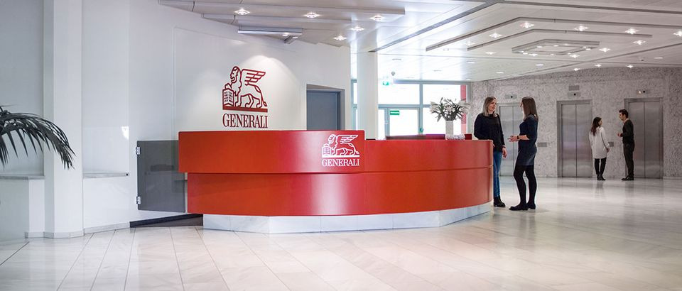 Jasne, przestronne wnętrze biura z recepcją Generali, gdzie dwie kobiety rozmawiają, a w tle widać osoby czekające na windy.