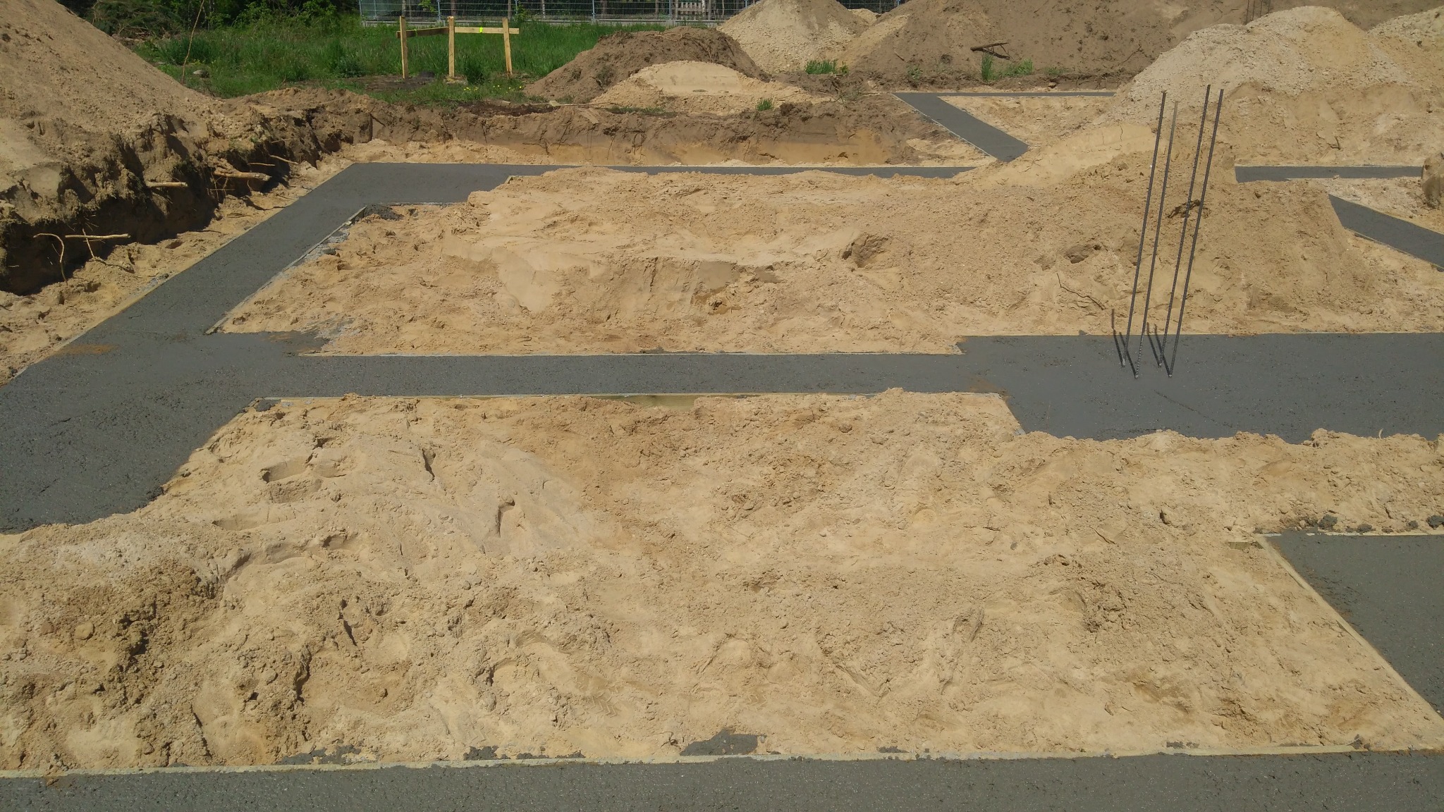 Wylane fundamenty pod budowę domu, widoczne zbrojenie i piasek zasypowy.