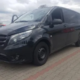 Czarny van Mercedes-Benz Vito Taxi z otwartymi drzwiami kierowcy, zaparkowany na brukowanym placu w Gdańsku. Tablica rejestracyjna widoczna.