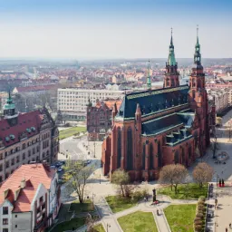 Panorama Legnicy z widokiem na Katedrę Legnicką i zabudowę miejską w słoneczny dzień.