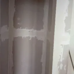 Wnęka ścienna w trakcie wyrównywania gładzią szpachlową, widoczne niedoskonałości i nierówności, przygotowanie pod malowanie.