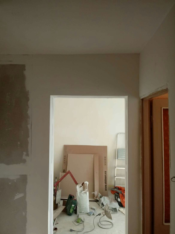 Przygotowanie ścian do malowania w trakcie remontu, widoczne niedokładnie wyszpachlowane ściany, narzędzia, drabina i płyty kartonowo-gipsowe.