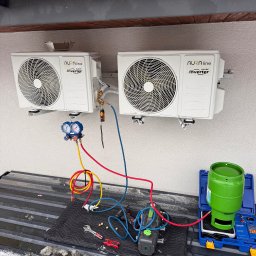 INSTAL4U - Dwa białe klimatyzatory Aura Line zamontowane na ścianie budynku, podłączone do narzędzi serwisowych, butla z czynnikiem chłodniczym obok. Prace serwisowe w toku.