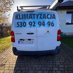 INSTAL4U - Tył białego samochodu dostawczego Peugeot Expert z reklamą firmy klimatyzacyjnej i numerem telefonu na tle domu i drzew.
