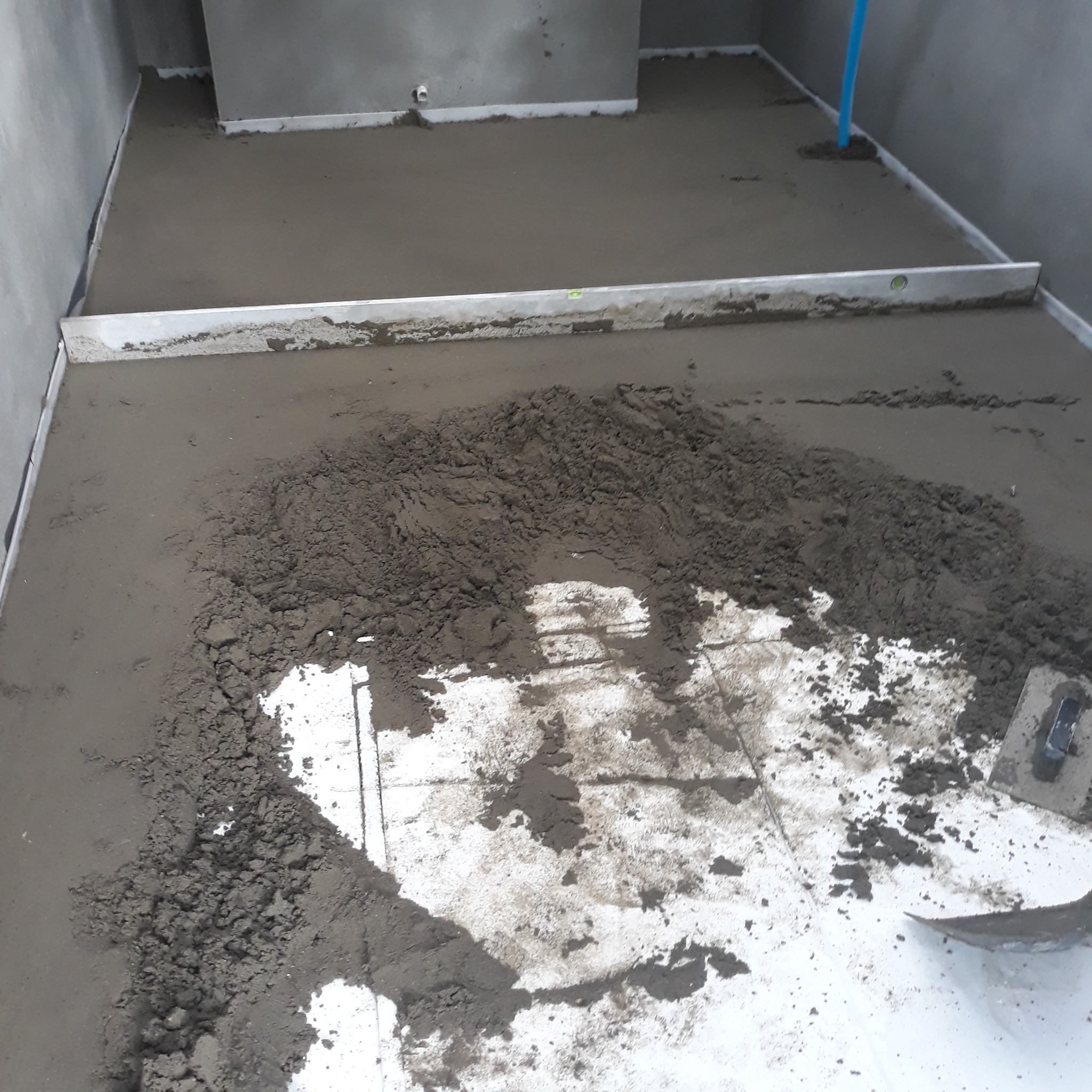 Wyrównywanie wylewki podłogowej w Zapałowie, widoczne narzędzia i poziomica.