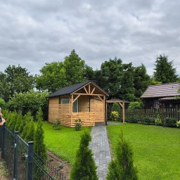 MAR-DACH Mariusz Boruc - Drewniana altana z zadaszeniem i ścieżką z kostki w Grębkowie, otoczona zielenią. Osoba opiera się o ogrodzenie w lewym dolnym rogu. Pochmurne niebo w tle.