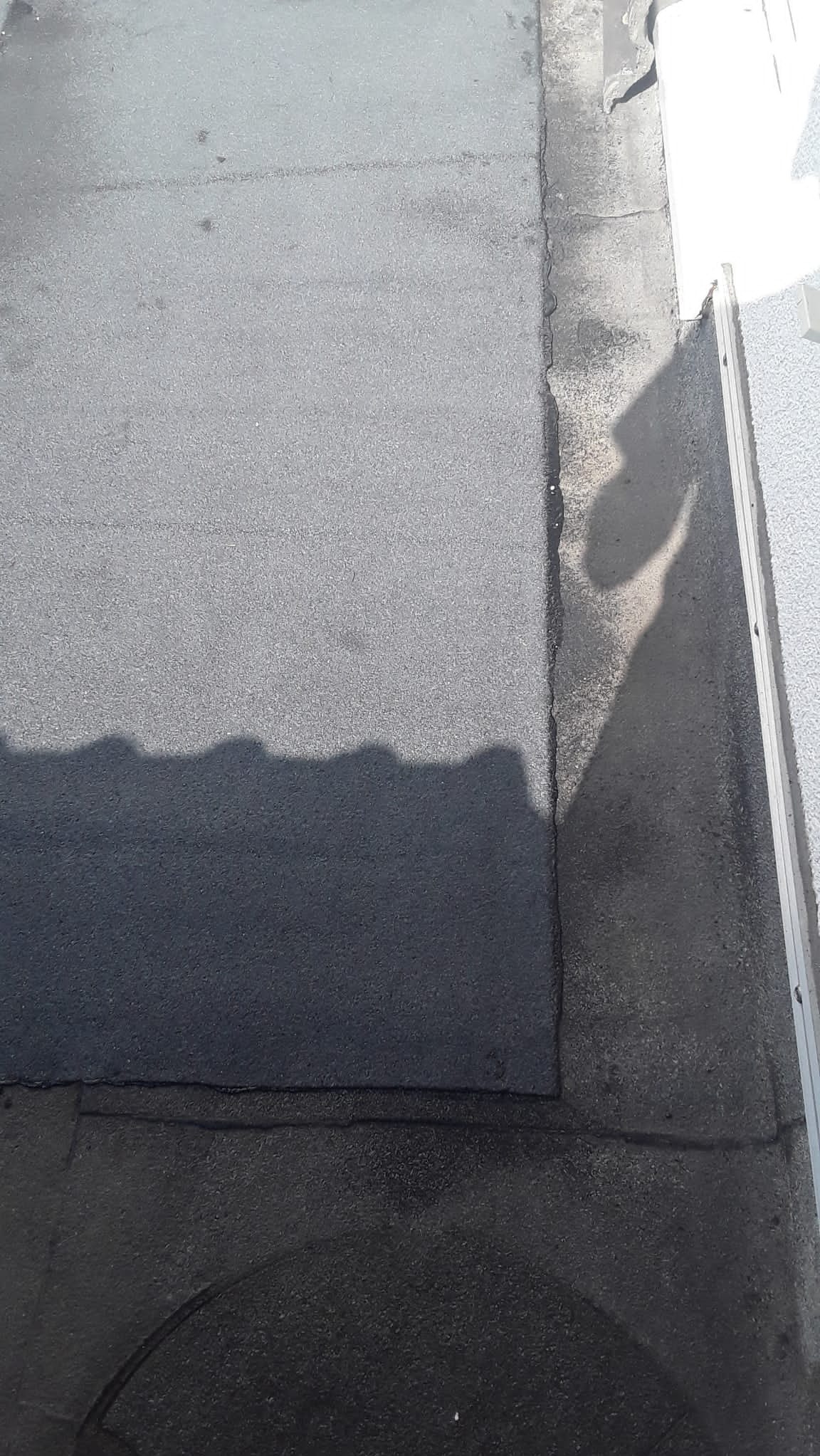 Fragment dachu pokrytego papą, widoczne łączenia i obróbki blacharskie. Kąt ujęcia z góry.