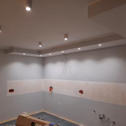 Lew instal - Wnętrze w trakcie remontu: przygotowane ściany pod zabudowę kuchenną z widocznymi puszkami instalacyjnymi, oświetlenie sufitowe typu downlight.