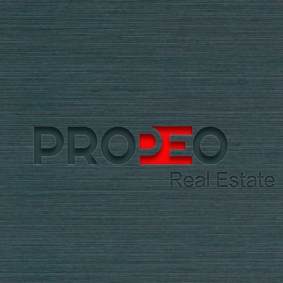 Logo firmy PRODEO Real Estate wytłoczone na szczotkowanym metalu z czerwonym akcentem w literze E.