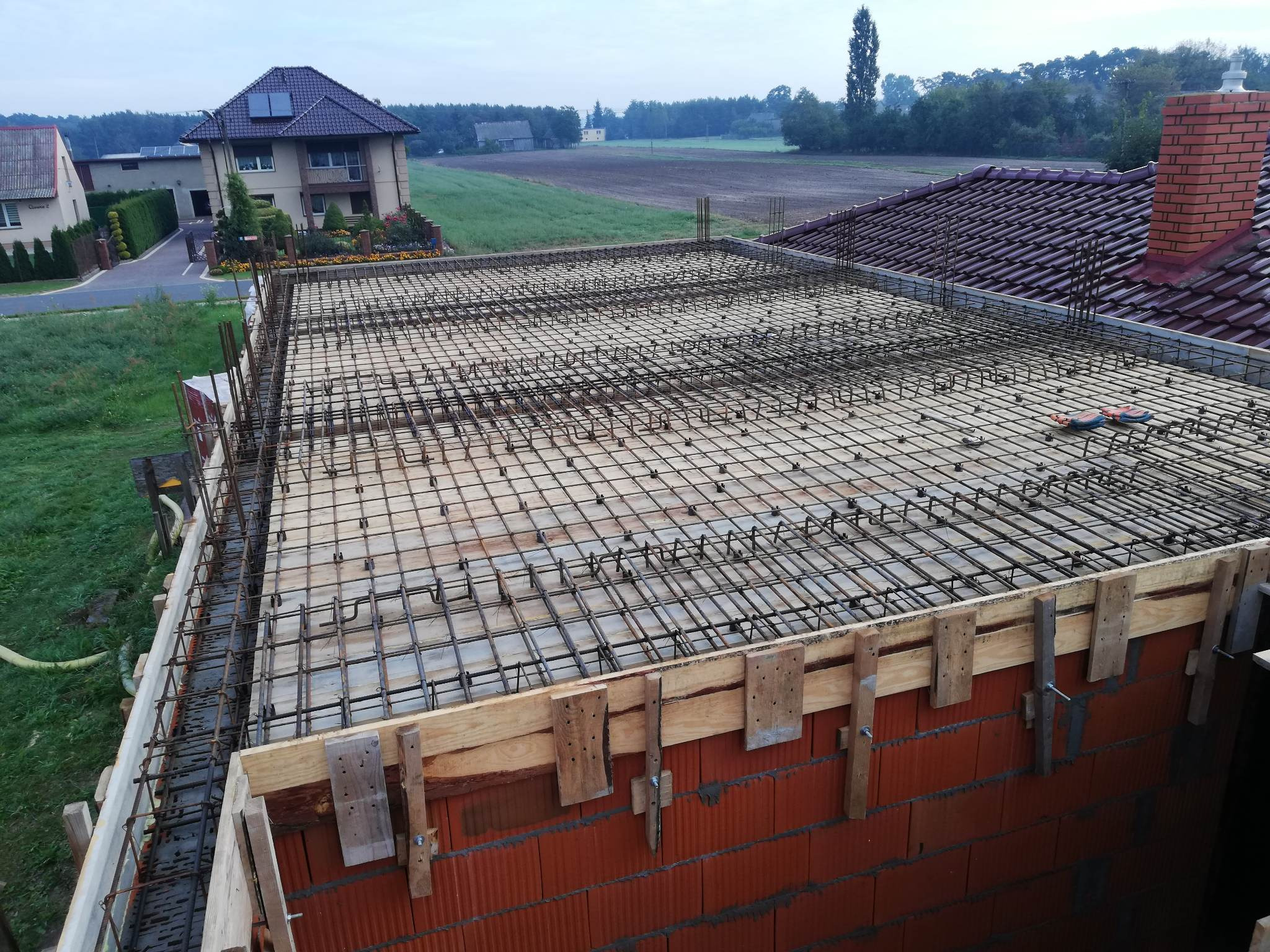 Zbrojenie płyty stropowej domu jednorodzinnego, widok z góry na siatkę z prętów stalowych, drewniane szalunki i pustaki ceramiczne.