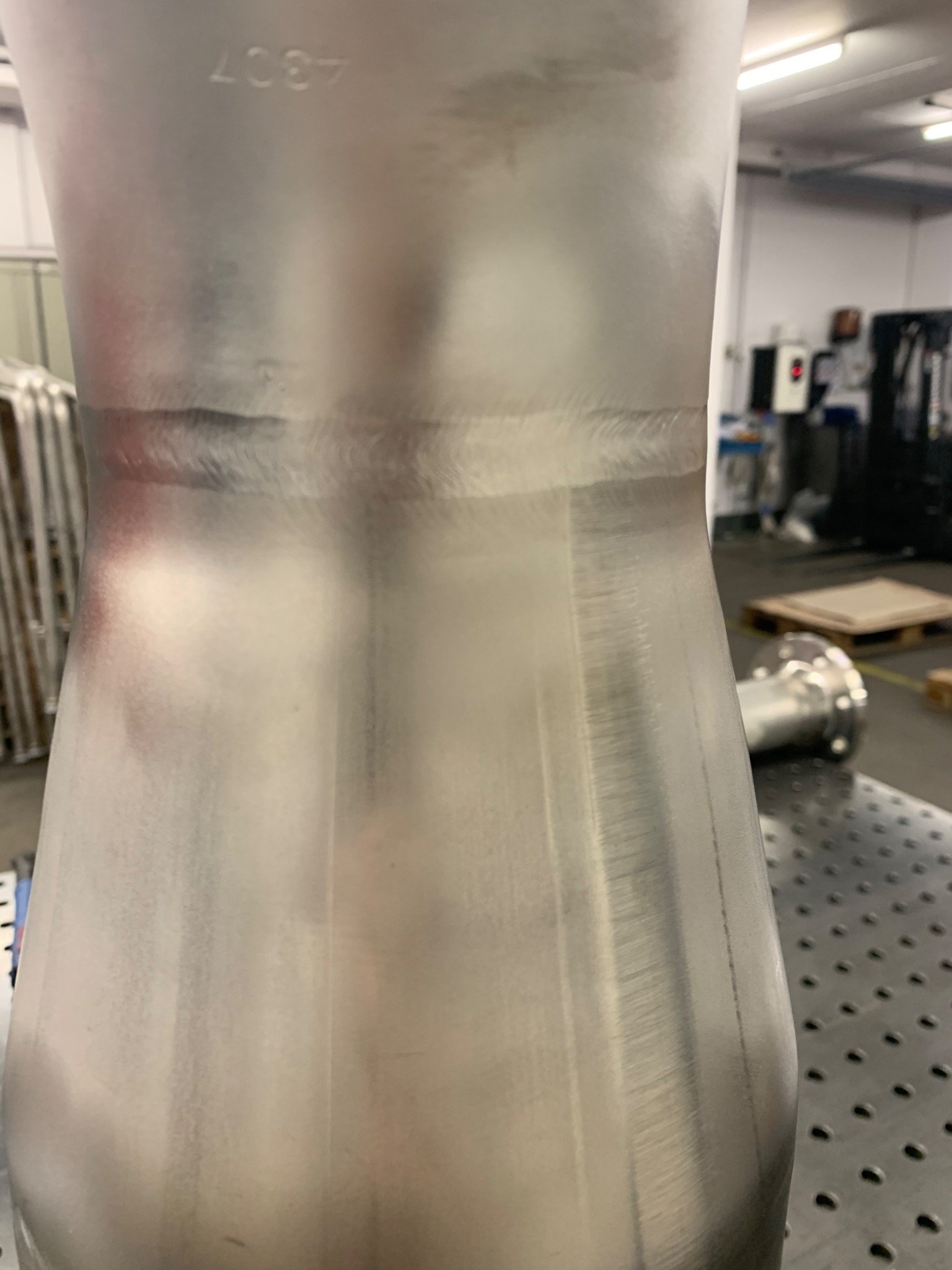 Szlifowany, spawany element ze stali nierdzewnej z widocznym numerem seryjnym 4307, umieszczony na perforowanym stole warsztatowym w hali produkcyjnej.