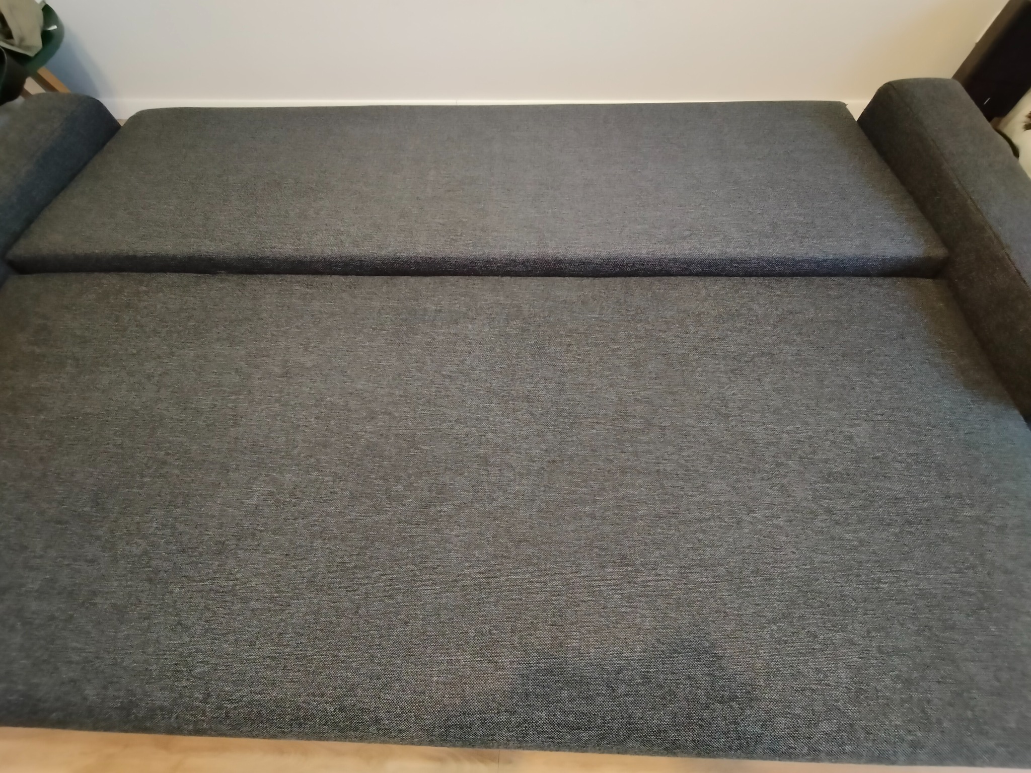 Szara kanapa z widoczną fakturą materiału, ujęcie z góry, widoczne załamania na siedzisku.