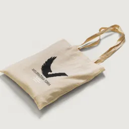 Beżowa torba bawełniana z czarnym nadrukiem stylizowanym na skrzydło i literę V oraz napisem 'WIELORAZOWA TORBA VESTRUM twój lojalny partner' leżąca na białym tle.