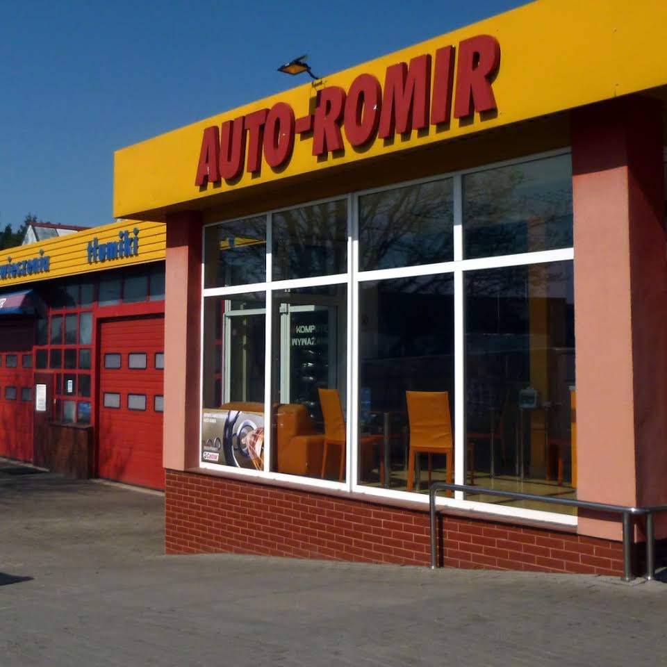 Fasada budynku warsztatu samochodowego Auto-Romir z żółtym szyldem i czerwonymi drzwiami garażowymi, widoczne wnętrze z krzesłami dla klientów i plakatem Castrol.