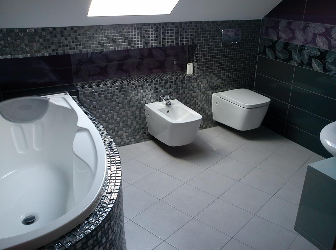 Wykończona łazienka w odcieniach szarości i bieli z mozaiką,  zawierająca wannę z hydromasażem, bidet i podwieszaną toaletę. Nowoczesny design.