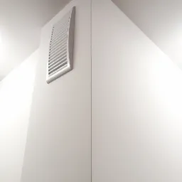 Biała kratka wentylacyjna z poziomymi szczelinami, zamontowana w rogu ściany i sufitu, świeżo po malowaniu.