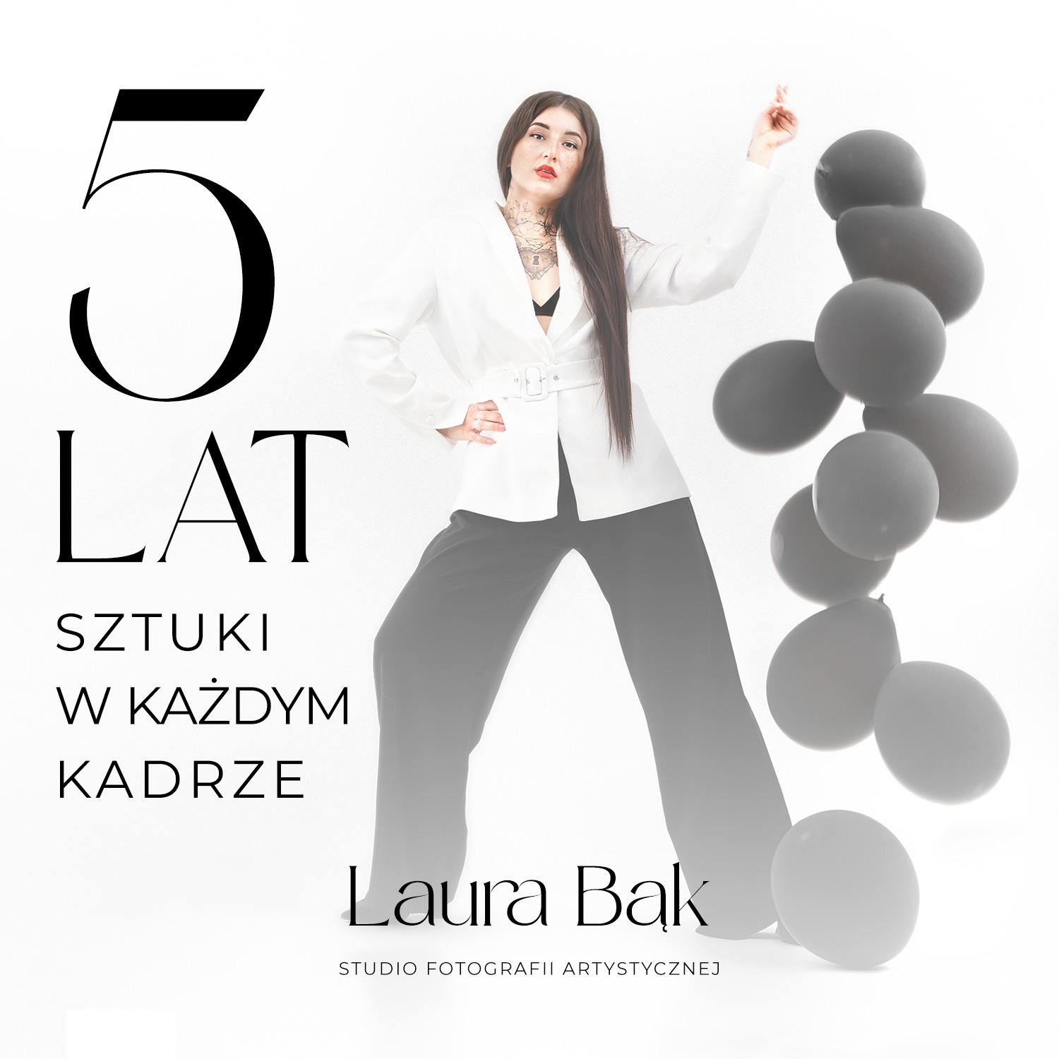 Portret kobiety w białej marynarce i czarnych spodniach, pozującej na tle białego tła z szarymi balonami i napisem '5 LAT SZTUKI W KAŻDYM KADRZE Laura Bak STUDIO FOTOGRAFII ARTYSTYCZNEJ'.