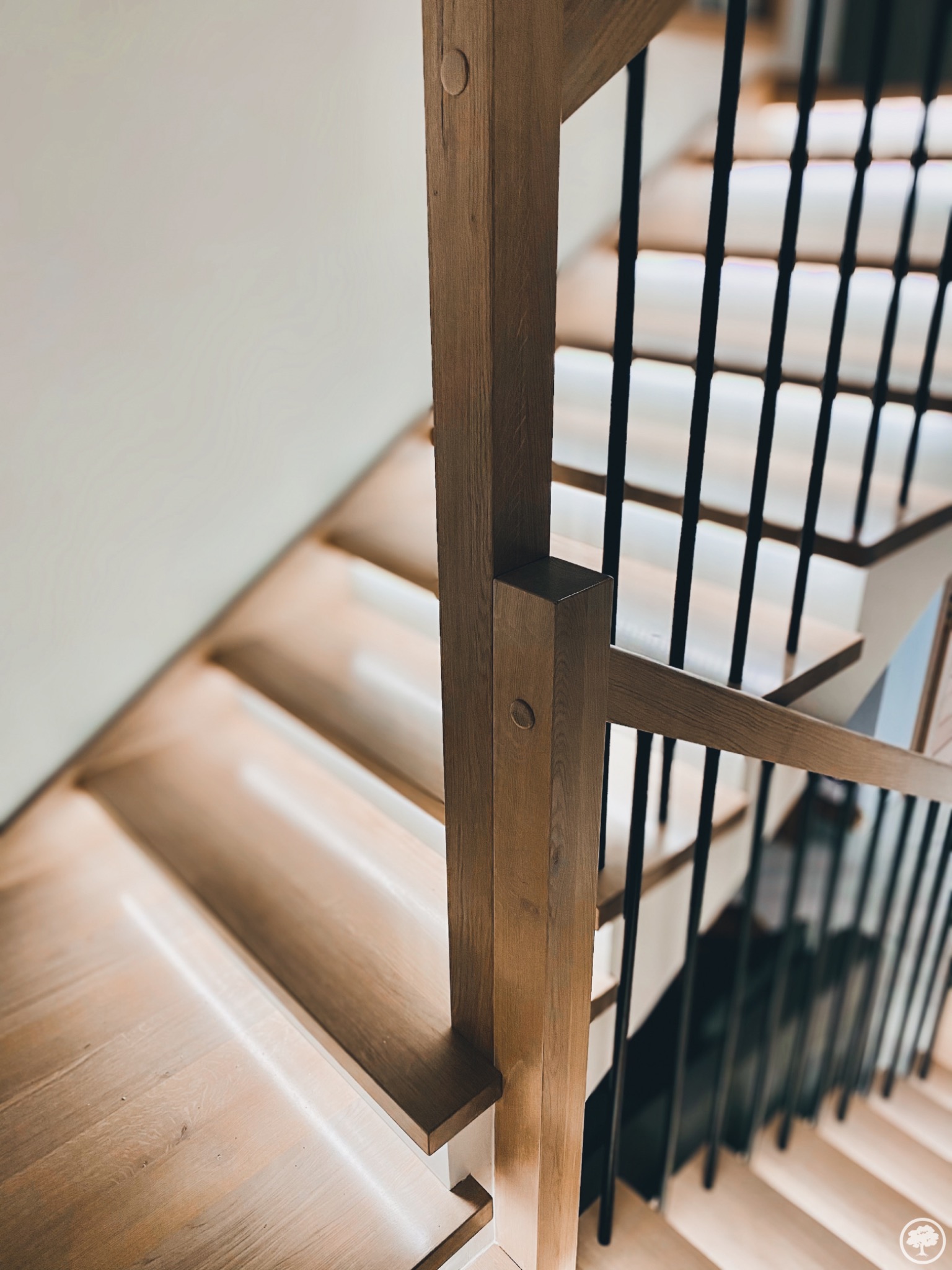 Nowoczesne schody drewniane z podświetleniem LED stopni i czarnymi, metalowymi balustradami, widok z góry na dół, jasne drewno.