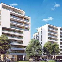 El-Mar - Wizualizacja dwóch nowoczesnych, białych budynków mieszkalnych z balkonami, otoczonych zielenią i zaparkowanymi samochodami w słoneczny dzień.