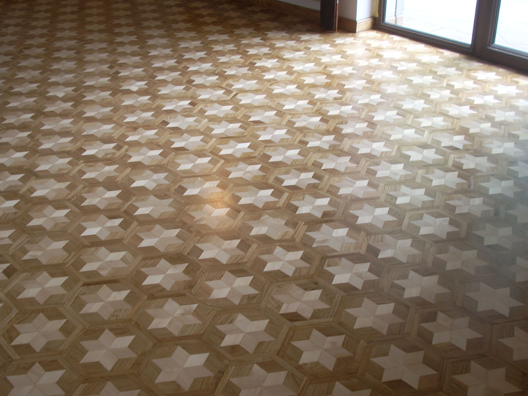Wzór parkietu ułożonego w gwiazdy na heksagonalnym tle, widok z góry w kierunku okna.