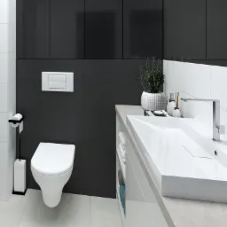 Nowoczesna łazienka w odcieniach bieli i grafitu z wiszącą miską WC, minimalistyczną umywalką nablatową i czarnymi szafkami pod sufitem.