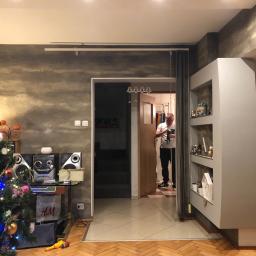 Uslugi Budowlane Piotr Towsciuk - Szara ściana z efektem betonu w salonie z choinką, widoczny mężczyzna w tle, dekoracje świąteczne