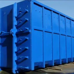 Nowy, pomalowany na niebiesko kontener stalowy na gruz lub inne odpady, widok z boku, widoczne mocowania i wzmocnienia konstrukcji.
