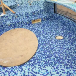 Wnętrze mozaikowej wanny jacuzzi w trakcie budowy, widoczne drewniane podpory, okrągła pokrywa i otwory na dysze.