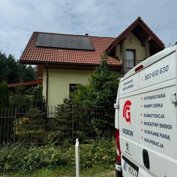Gedeon Wróblewski Sp.j - Dom jednorodzinny z panelami słonecznymi na dachu, widok zza firmowego samochodu z logo 'Gedeon' i listą usług: fotowoltaika, pompy ciepła, klimatyzacja, magazyny energii, ocieplanie pianą...