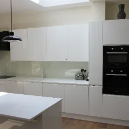 Nowoczesna, minimalistyczna kuchnia z białymi, błyszczącymi frontami, wyspą kuchenną i czarnym piekarnikiem marki Bosch. Oświetlenie punktowe oraz dekoracyjna waza na szafce dodają charakteru.