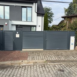 Z.P.H.U. ANMAR Marcin Majkowski - Nowoczesna, pozioma brama lamelowa w kolorze antracytu, z furtką i skrzynką elektryczną, na tle domu z szarą elewacją i kostki brukowej.