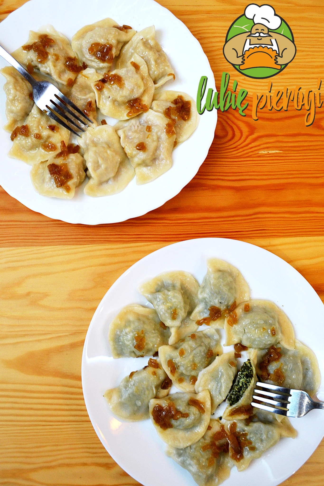 Dwa białe talerze z pierogami okraszone podsmażoną cebulką, na drewnianym stole. Jeden pieróg z farszem szpinakowym przekrojony widelcem.