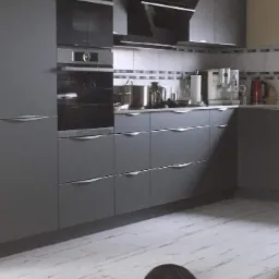 Szara kuchnia z zabudową, piekarnikiem i płytą grzewczą, na podłodze leży kot.