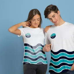 Dwoje młodych ludzi pozuje w białych koszulkach z nadrukowanym logo i motywem fal na błękitnym tle.