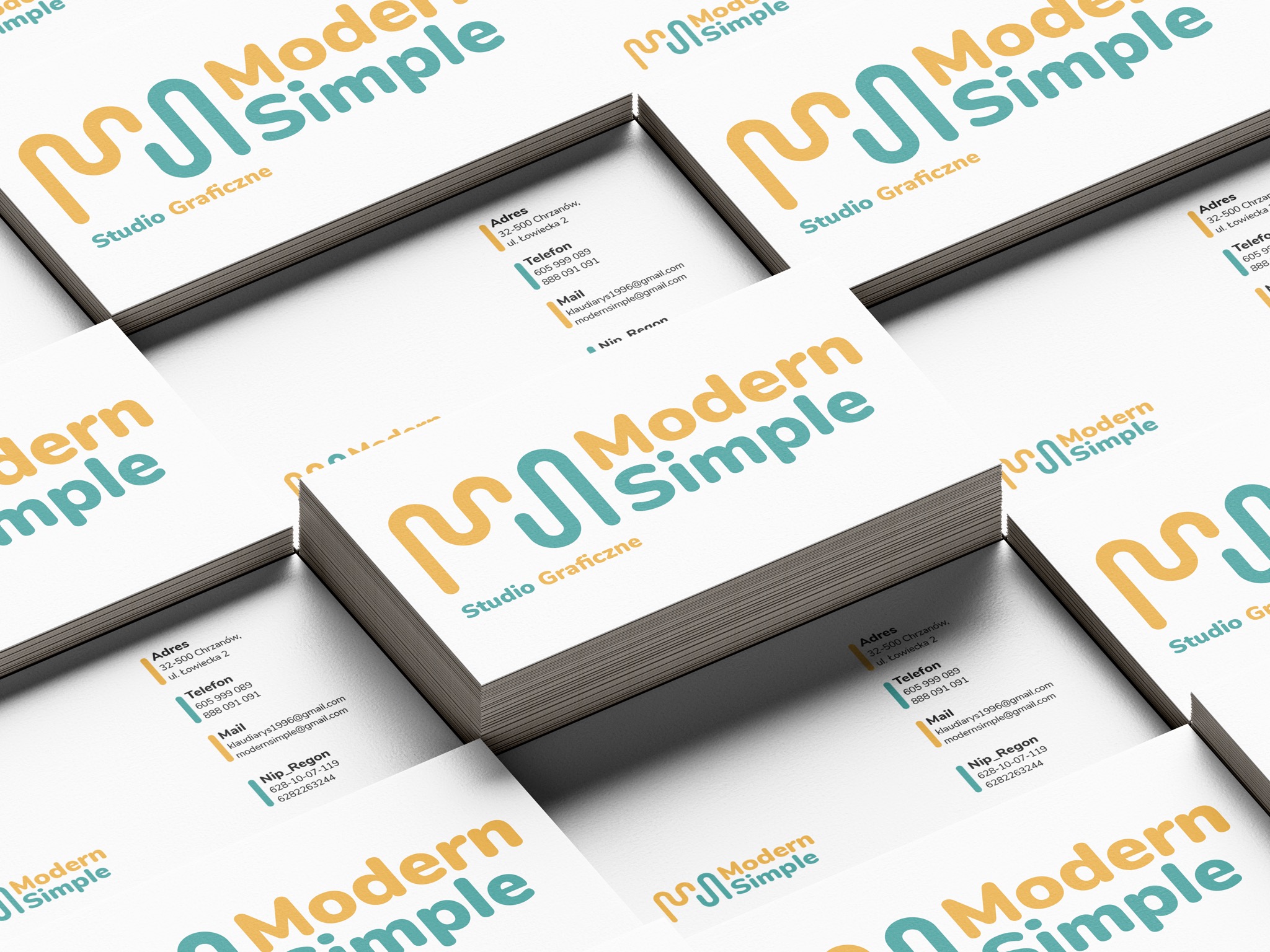 Stos wizytówek z minimalistycznym logo 'Modern Simple' w kolorach żółtym i turkusowym, ułożonych pod kątem, z widocznymi danymi adresowymi i kontaktowymi.