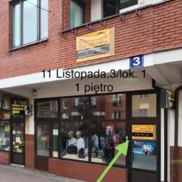 Fasada budynku z szyldem 'Psychotechnika' nad wejściem, adres 11 Listopada 3/lok. 1, pierwsze piętro, widoczne manekiny w witrynie i strzałka wskazująca wejście od deptaku.
