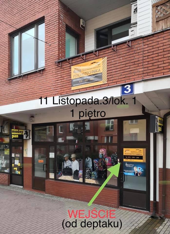 Fasada budynku z szyldem 'Psychotechnika' nad wejściem, adres 11 Listopada 3/lok. 1, pierwsze piętro, widoczne manekiny w witrynie i strzałka wskazująca wejście od deptaku.