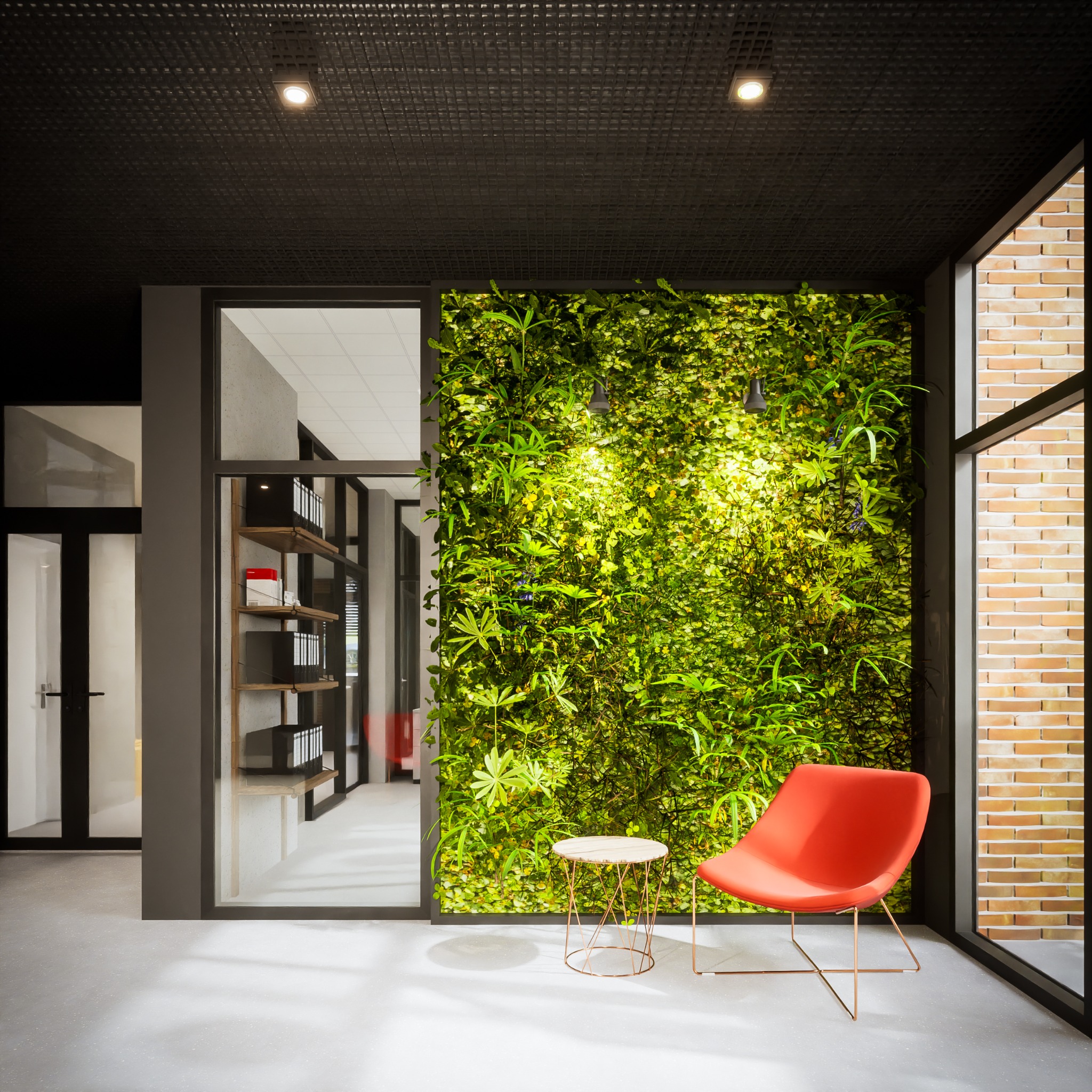 Wnętrze biurowe z ścianą z zielonych roślin, czerwonym krzesłem i stolikiem kawowym na metalowych nóżkach, widok na korytarz z regałami na dokumenty, oświetlenie punktowe