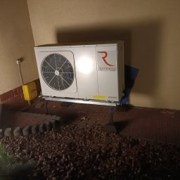 INSTALFIX - Biała pompa ciepła marki Rotenso zamontowana na zewnątrz budynku, widoczna instalacja gazowa w żółtej obudowie.