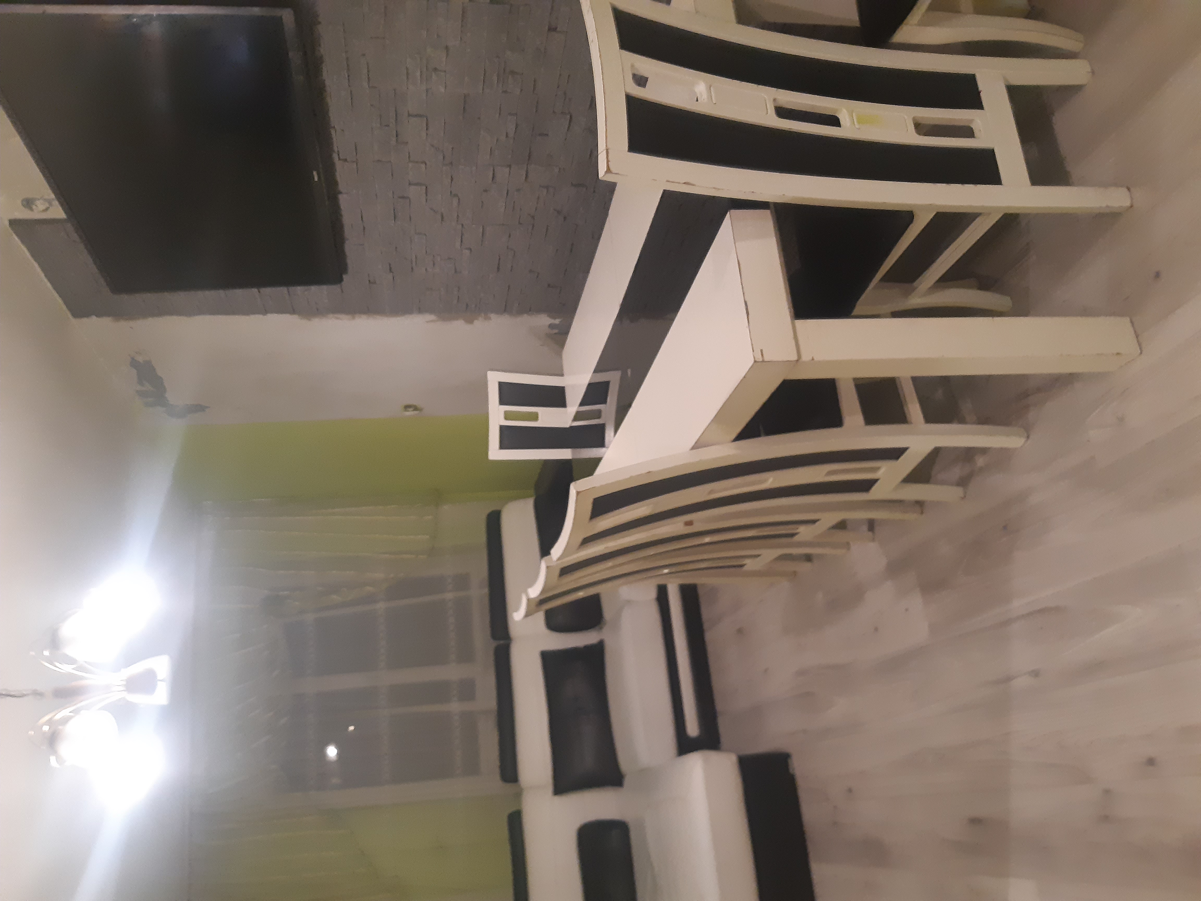 Wnętrze w Limanowej w trakcie wykańczania: biało-czarne meble, surowa ściana z cegły dekoracyjnej, widoczny fragment instalacji elektrycznej i oświetlenie sufitowe.