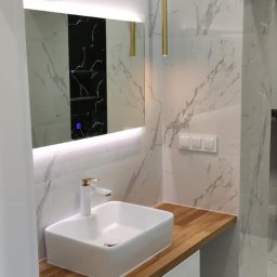 AQUA-TERM2 - Nowoczesna łazienka z umywalką nablatową na drewnianym blacie, podświetlanym lustrem i marmurowymi płytkami.