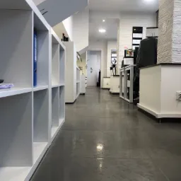 Jasne, przestronne wnętrze biurowe z białymi regałami i szarą podłogą z płytek, widok z perspektywy podłogi wzdłuż korytarza.