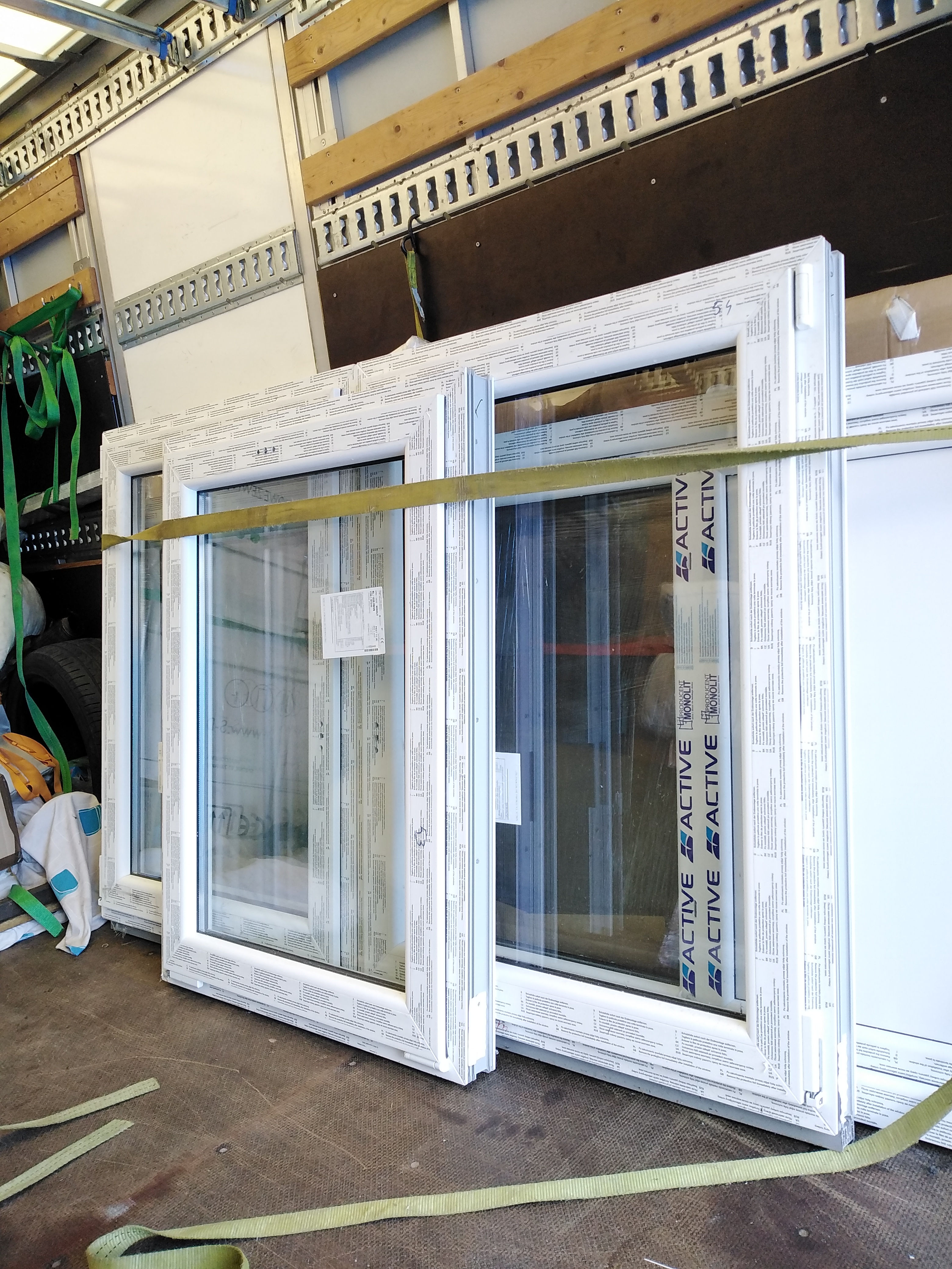 Transport okien PCV zabezpieczonych pasami wewnątrz pojazdu w Druten. Widoczne etykiety producenta i folia ochronna na szybach.