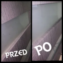 Porównanie 'przed' i 'po' czyszczeniu matowej szyby w meblu z drewnopodobną okleiną. Lewa strona szyby jest brudna, z widocznymi smugami i plamami, prawa strona jest czysta i przejrzysta.