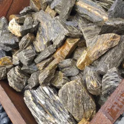 Kopalniane kamienie dekoracyjne w drewnianej skrzyni, z widocznymi warstwami i smugami w odcieniach szarości, brązu i bieli.