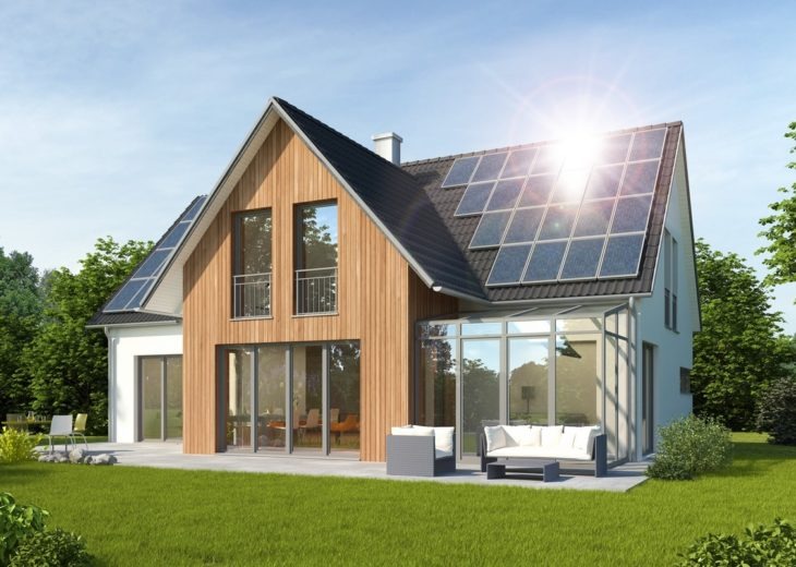 Nowoczesny dom jednorodzinny z panelami słonecznymi na dachu, widok z ogrodu z meblami wypoczynkowymi