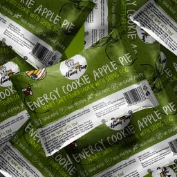 Krasovski.pl - Zbliżenie na zielone opakowania ciastek energetycznych Honey Trap z jabłkiem i nasionami, ułożone warstwami, z widocznymi informacjami o składzie i wartościach odżywczych.